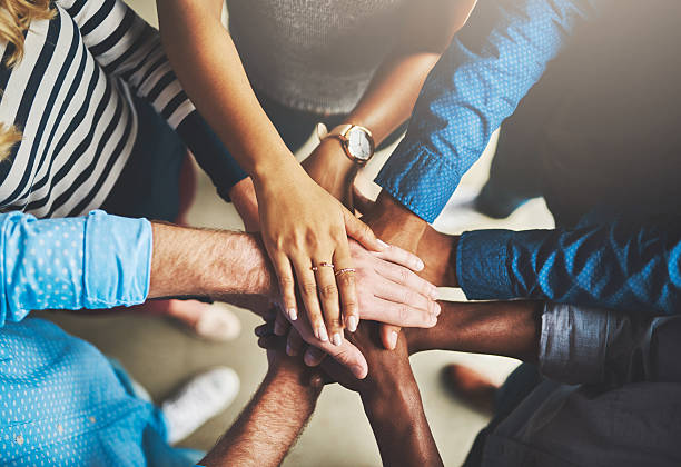 Photo d'un groupe d'entrepreneurs créatifs debout, les mains jointes, formant un cercle